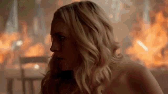 a woman is standing in front of a fire in a room .