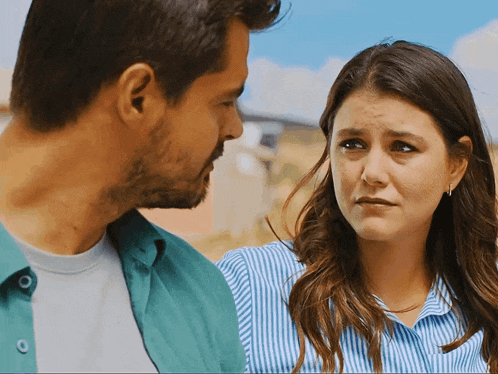 a man and a woman are looking at each other and the woman is looking sad