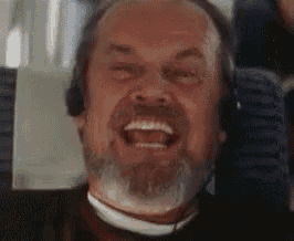 a man with a beard and headphones is smiling while sitting on a plane .