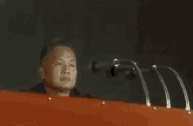 a man is sitting in front of a podium with microphones .