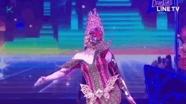 a drag queen is performing on stage in front of a screen that says line tv