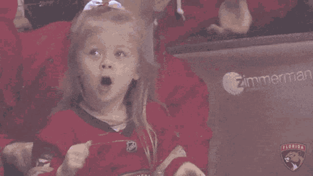a little girl wearing a panthers jersey screams in the stands
