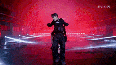 a man in a black uniform is dancing in front of a red background that says stu 1