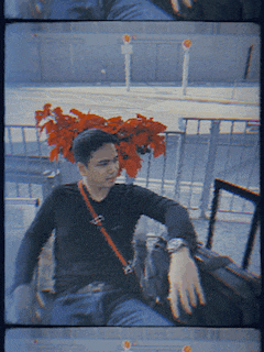 a man wearing a black shirt with a red strap around his shoulder looks at his watch