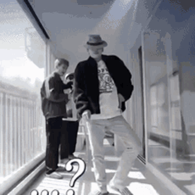 a man in a hat is standing in a hallway with a question mark in the corner