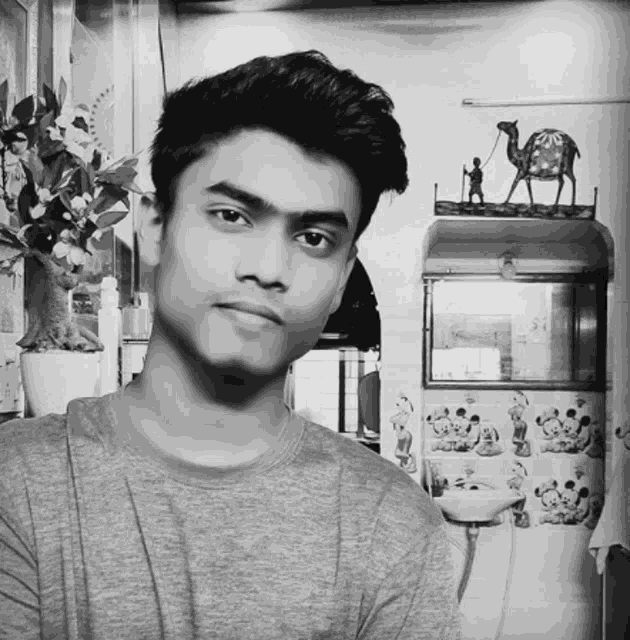 a black and white photo of a young man standing in front of a wall with a picture of a camel on it