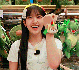 a woman is holding a stuffed animal on her wrist and smiling .