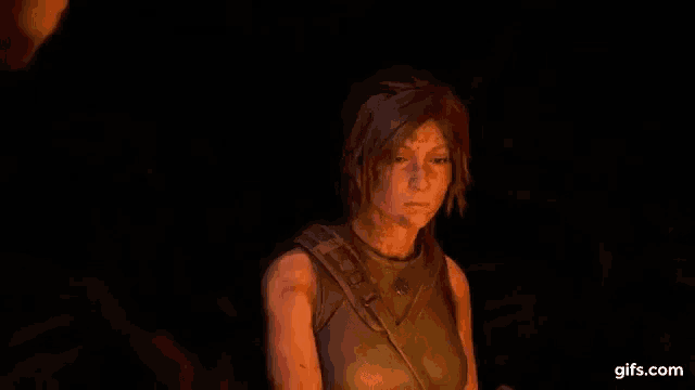 a woman with tattoos on her face is standing in a dark room .