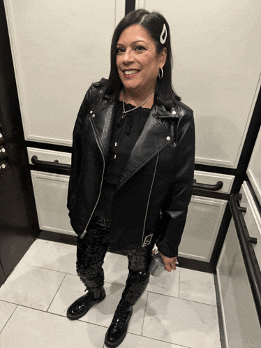 a woman in a black leather jacket and sequined pants