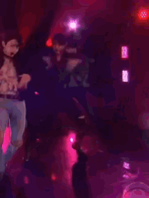 a man is dancing on a stage in a dark room with purple lights behind him .