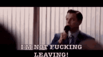 a man in a suit and tie is holding a microphone and saying `` i 'm not fucking leaving ! ''