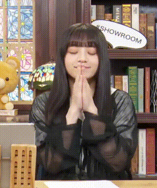 a woman with her eyes closed is sitting at a table with her hands folded in prayer .