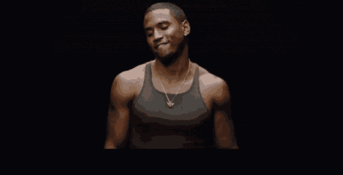 a man wearing a tank top and a necklace is smiling .