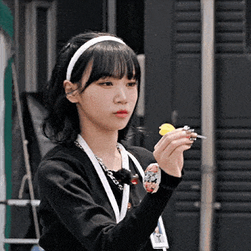a girl wearing a headband and a lanyard is holding a dart