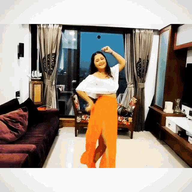 a woman is dancing in a living room with a couch and chairs