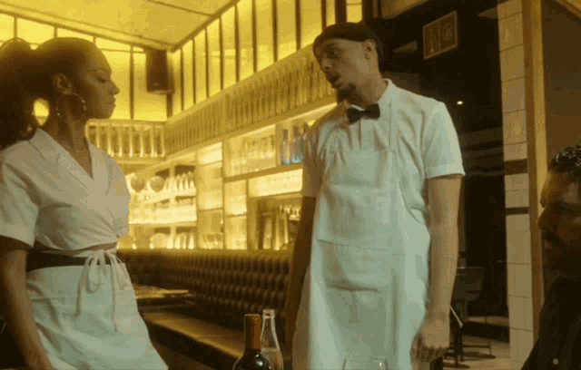 a man in a white apron is standing next to a woman