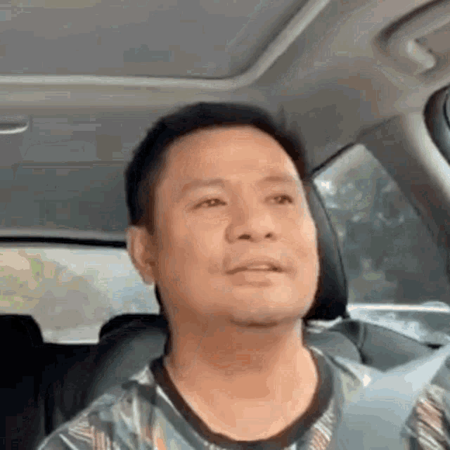 a man is sitting in the back seat of a car and making a funny face .