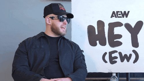 a man stands in front of a sign that says hey