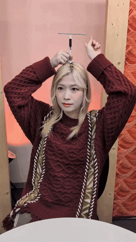 a woman in a maroon sweater is holding a pen in her hand