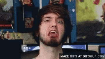 a man with a beard is making a funny face while sitting in front of a computer