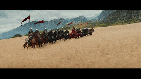 a group of men riding horses with mountains in the background