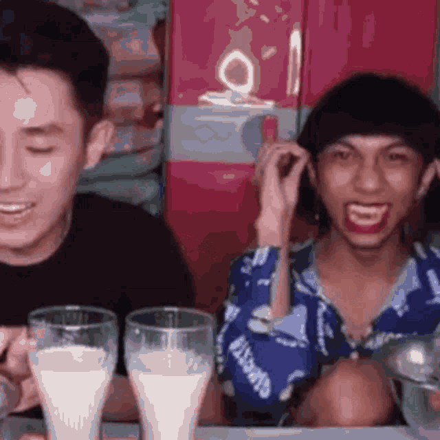 a man and a woman are sitting at a table drinking milk .