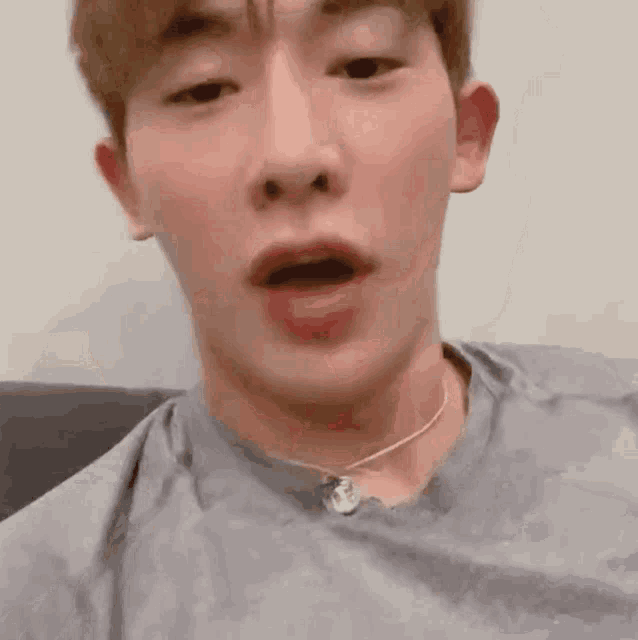 a close up of a man wearing a necklace and a t-shirt .