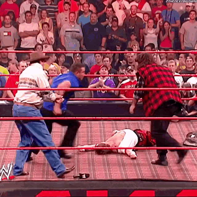 a group of men are wrestling in a wrestling ring with a crowd watching .