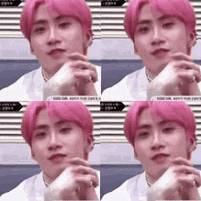 a young man with pink hair is sitting down with his hand on his chin and looking at the camera .