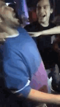 a group of people are standing next to each other in a room and having a fight .