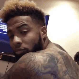 a man with a beard and tattoos looks over his shoulder at the camera