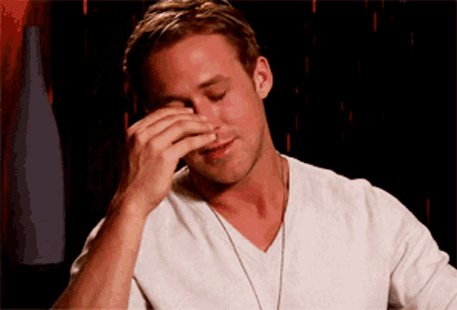 a man in a white shirt is covering his nose with his hand