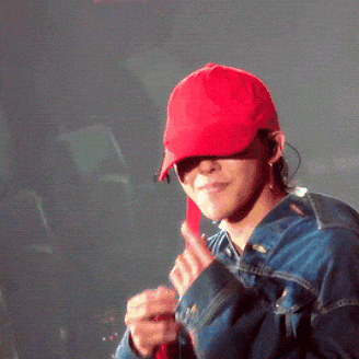 a man wearing a red hat and a denim jacket is giving a thumbs up