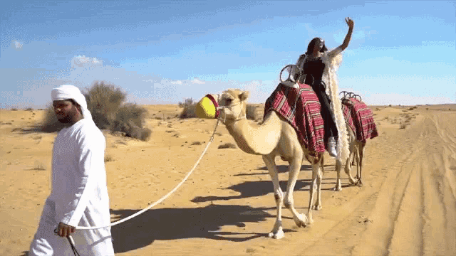a woman riding on the back of a camel being pulled by a man