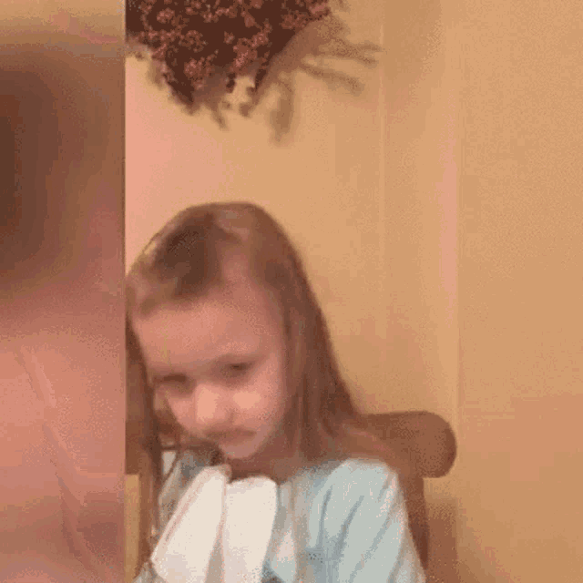 a little girl is sitting in a chair with a napkin in her mouth .
