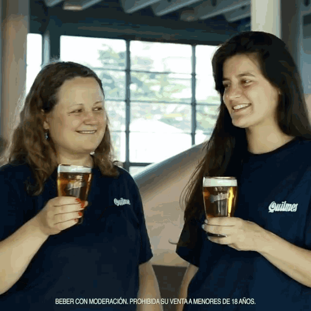 two women wearing quilmos shirts toasting with glasses of beer