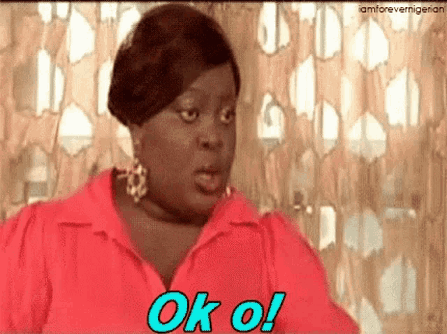 a woman in a red shirt is making a funny face and saying ok oi .