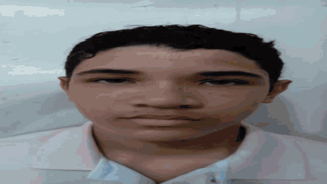 a close up of a young man 's face with a pink shirt on