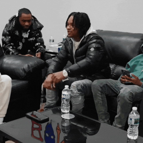 a bottle of aquafina water sits on a table next to a group of men