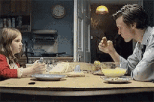 a man and a little girl are sitting at a table with plates of food