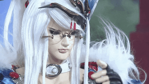 a doll with long white hair and glasses is holding a feather .