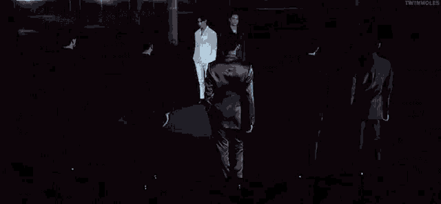 a group of men in suits are standing next to each other in the dark .