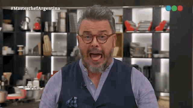 a man with glasses and a beard is making a funny face in front of a screen that says masterchef argentina