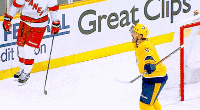 a hockey player stands on the ice in front of a great clips banner