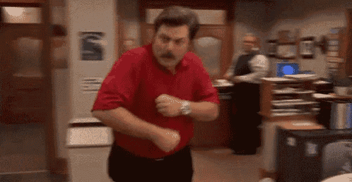a man in a red shirt is dancing in a room in an office .