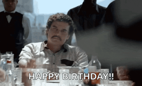 a man with a mustache is sitting at a table and saying happy birthday