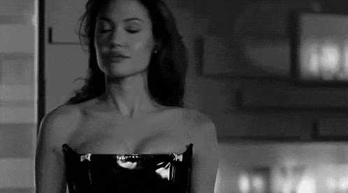 a black and white photo of a woman in a black leather dress .