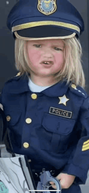 a little girl is dressed in a police officer costume and holding a gun .
