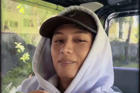 a man wearing a hoodie and hat is smiling