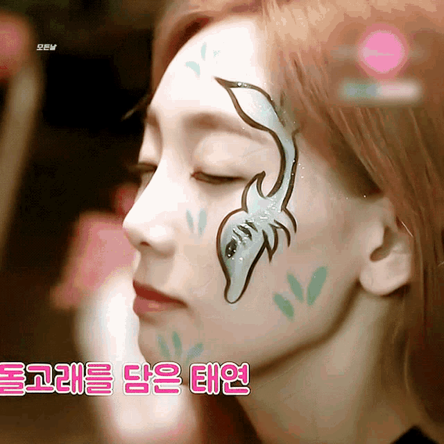 a close up of a woman 's face with a dolphin painted on her face